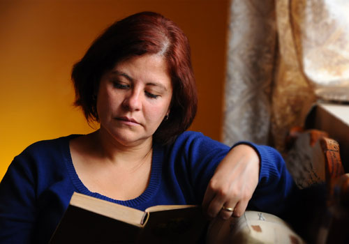 Adult Summer Reading Image of a woman relaxed and reading by a window
